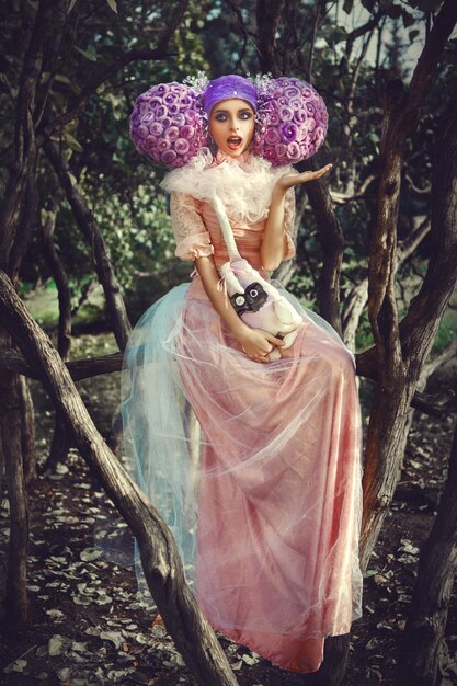 Schönes Modell, das rosa Kleid trägt, das mit einer lila Perücke aufwirft