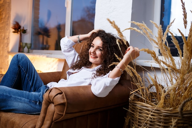 Foto schönes modell des jungen mädchens mit der lockenaufstellung. sie trägt ein weißes hemd und jeans.