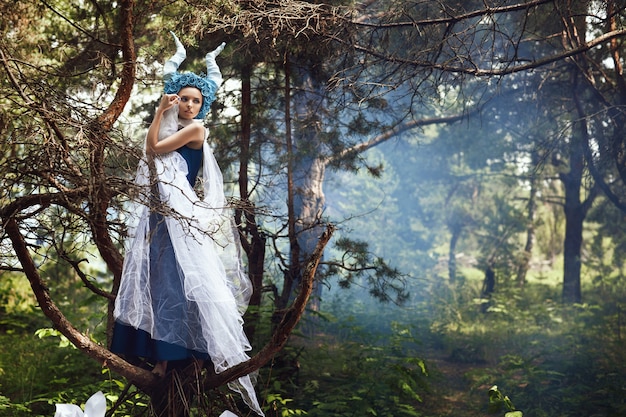 Schönes Modell posiert in einem Wald mit blauen Hörnern