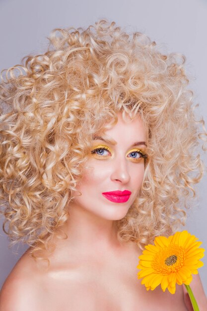 Schönes modisches blondes Mädchen im Retro-Stil mit voluminöser lockiger Frisur