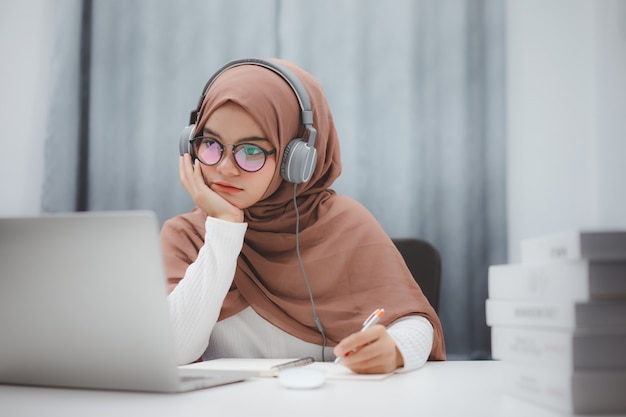 Schönes muslimisches Studentenmädchen, das einen Laptop verwendet, der online zu Hause lernt. Online-Fernunterricht.