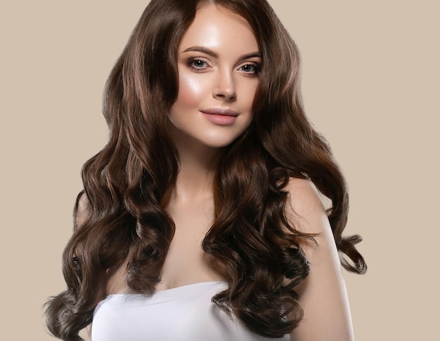 Schönes natürliches haarhautfrauenporträt bilden lange lockige haare. hintergrundfarbe braun