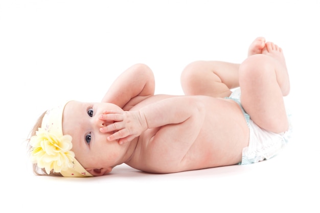 Schönes nettes Baby in der gelben Blumenverpackung liegt an zurück