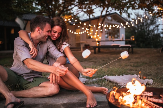 Schönes Paar, das Marshmallows in einem Hinterhof röstet