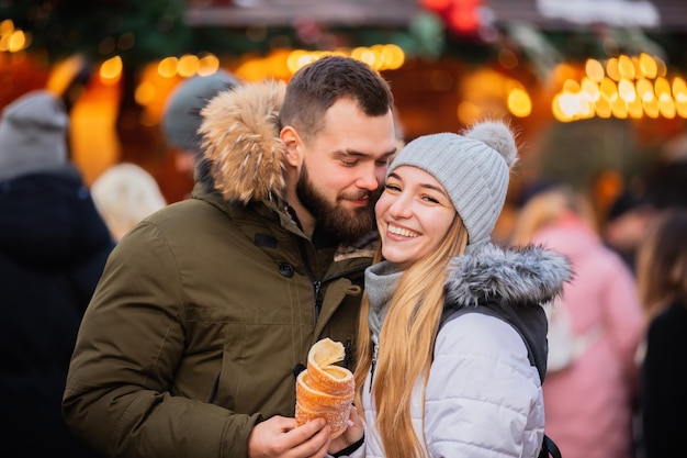 Schönes Paar isst tschechischen Trdelnik auf dem Weihnachtsmarkt in Breslau, Polen