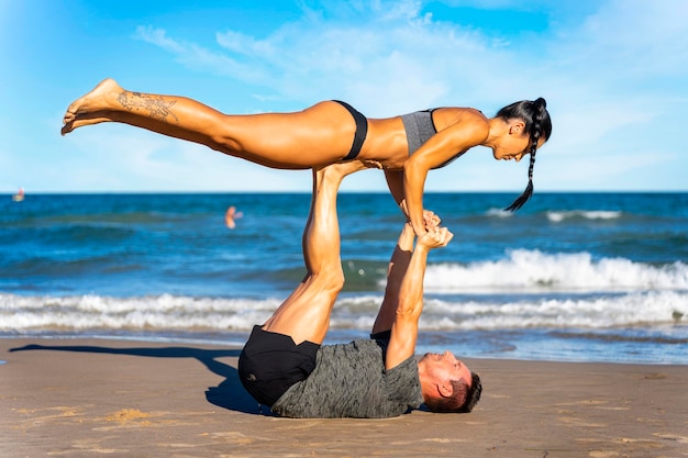 Schönes Paar macht Acro-Yoga am Strand