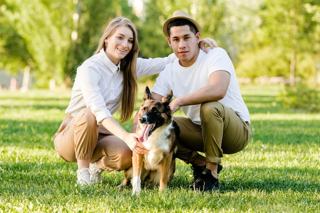 Schönes Paar mit ihrem Hund, der Spaß im Park hat