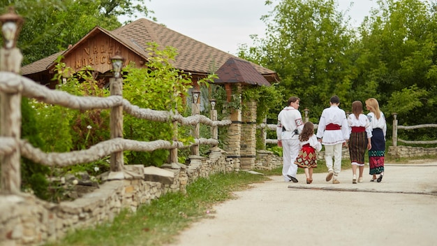 Schönes Paar mit ihren Kindern in traditioneller Tracht, die zusammen in Richtung Dorf gehen