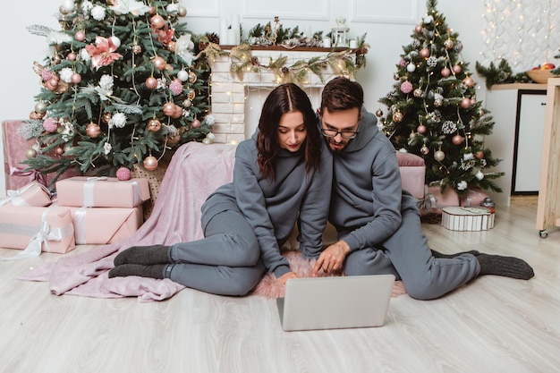 Schönes Paar mit Laptop kaufen Geschenke Geschenke im Internet Girlanden nach Hause gemütliche Innenatmosphäre