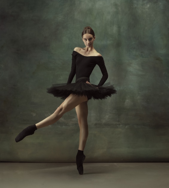 Schönes Porträt. Anmutiger klassischer Ballerinatanz, posiert einzeln auf dunklem Studiohintergrund. Eleganz schwarzes Tutu. Anmut, Bewegung, Aktion und Bewegungskonzept. Sieht schwerelos aus. Modisch.