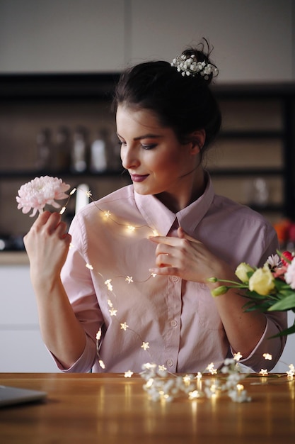 Schönes Porträt der Frau mit Lichtern und Blumen Feiertagsfeierkonzept Valentinstag Frauentag Kreativer Florist