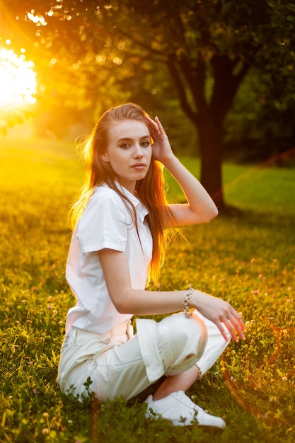 Schönes Porträt der jungen Frau bei Sonnenuntergang