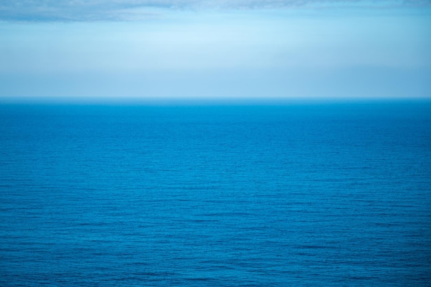 Schönes ruhiges und friedliches Wasser, das tagsüber mit Wellen in Richtung Strand mit grünen hohen Bäumen gegen bewölkten blauen Himmel fließt, ohne dass Menschen in der Nähe sind