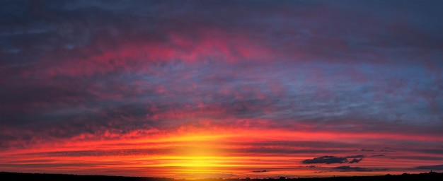 Schönes sanftes Sonnenuntergangspanorama mit großen Wolken über einer kleinen Stadt