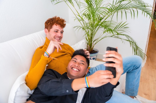 Schönes schwules Paar, das drinnen auf dem Sofa romantisch ist schwules Paar, das ein Selfie macht