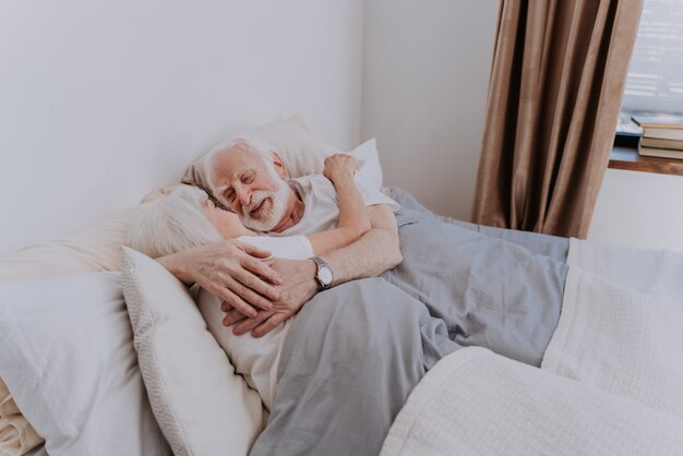 Schönes Seniorenpaar genießt die gemeinsame Zeit zu Hause - Romantische Momente zu Hause, älteres Ehepaar im Bett zu Hause