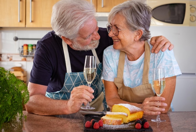 Foto schönes seniorenpaar in der heimischen küche, das ein glas wein hält, das bereit ist, seinen hausgemachten pflaumenkuchen zu essen, der mit beeren serviert wird kochen zu hause für das familienkonzept