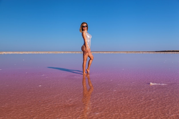 Schönes sexy Mädchen, das auf einem rosa salzigen See aufwirft. Fotoshooting eines gebräunten Mädchens auf einem salzigen rosa See.