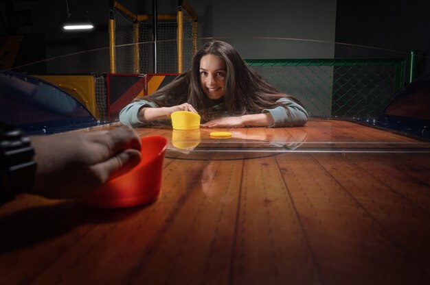 Foto schönes sportmädchen spielt airhockey im unterhaltungszentrum. kinderpark. familienurlaub. gemischte medien