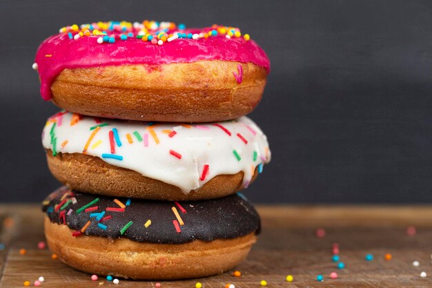 Schönes süßes Essen Stapel von glasierten bunt sortierten Donuts mit Spritzern auf grauem Hintergrund