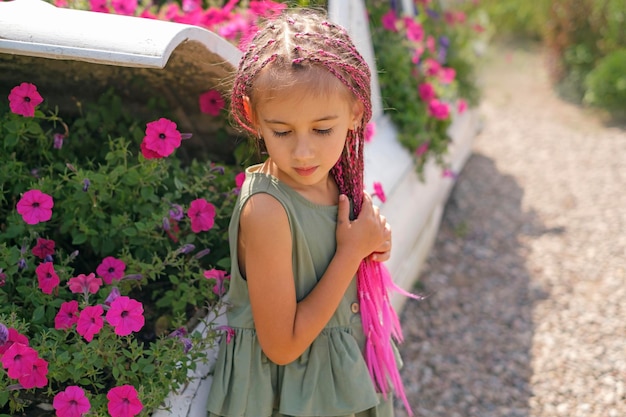 Schönes süßes Mädchen mit rosa langen Afro-Zöpfen sieht weg