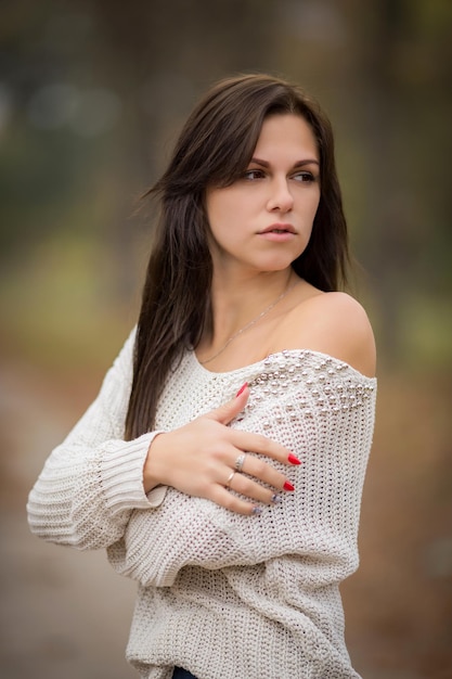 Schönes trauriges Mädchen im Herbstpark in einem beigen Pullover Hochwertiges Foto