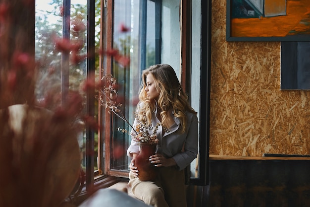 Schönes und authentisches blondes Modellmädchen mit blauen Augen im modischen Outfit, das am Loft-Innenraum aufwirft