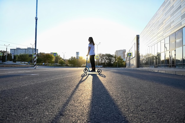 Schönes und blondes Mädchen übt Longboard auf der Straße