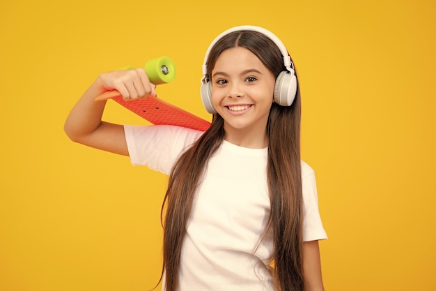 Schönes und modisches junges Teenager-Mädchen, das mit Skateboard aufwirft Teenager-Streetmode-Lebensstil Glückliches Teenager-Porträt Lächelndes Mädchen