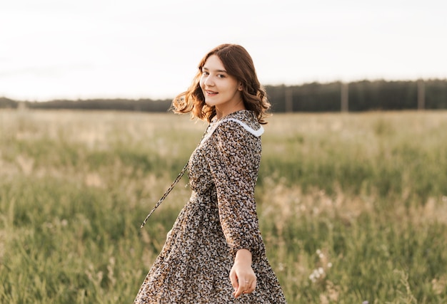 Schönes und sanftes Teenager-Mädchen in einem Kleid geht und entspannt sich im Sommer in der Natur