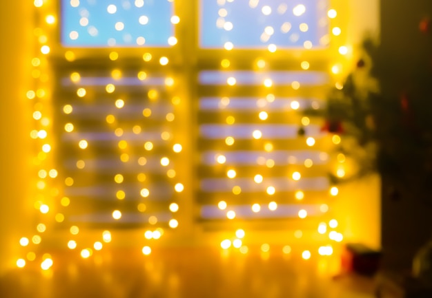 Schönes unscharfes flackerndes gelbes Licht. Heimtextilien mit Girlanden am Fenster, Nacht-Bokeh-Beleuchtung. Festlicher Hintergrund.