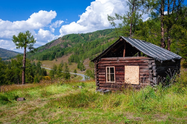 Schönes verlassenes Holzblockhaus auf Gebirgshintergrund