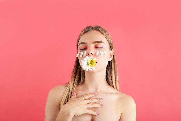 Schönes vorbildliches Mädchen mit Blumen auf rosa Hintergrund