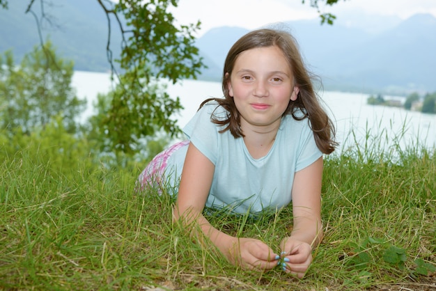 Schönes vorjugendliches Mädchen, das im Gras liegt