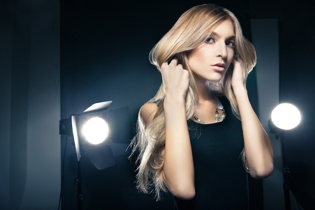Schönes weibliches Model posiert im Studio in den Lichtblitzen