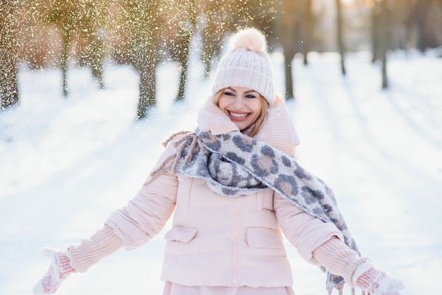 Schönes Winterporträt der jungen Frau in der schneebedeckten Winterlandschaft