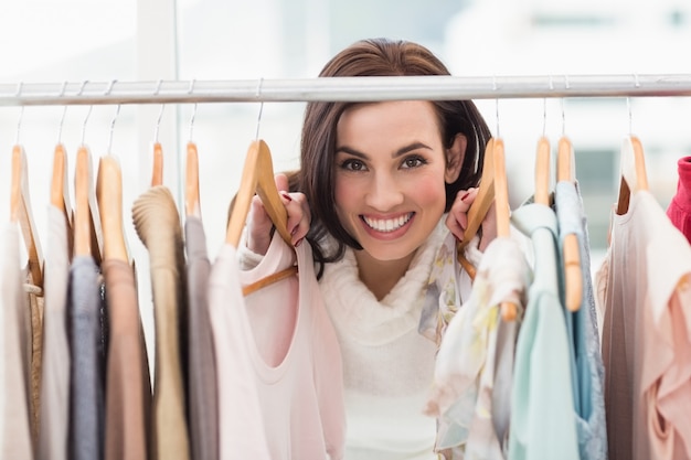 Schönheit Brunette, der an der Kamera durch Kleidungsschiene lächelt