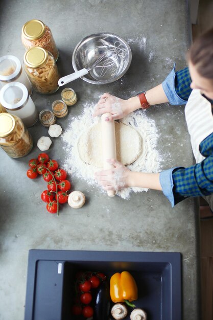 Schönheit, die Kuchen in der Küche kocht, die nahe Schreibtisch steht