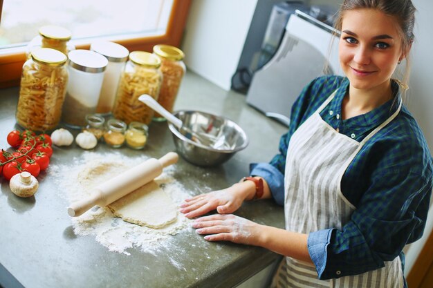 Schönheit, die Kuchen in der Küche kocht, die nahe Schreibtisch steht