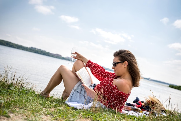 Schönheit, die nahe dem Sommertag des Sees sitzt