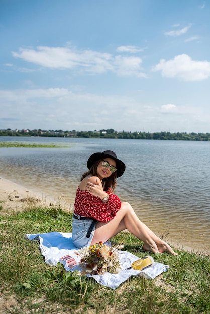 Schönheit, die nahe dem Sommertag des Sees sitzt