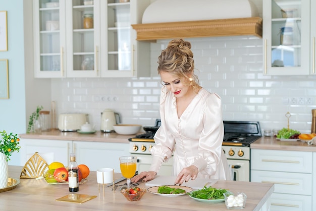 Schönheit, die organischen vegetarischen Salat kocht, der Erdbeeren schneidet