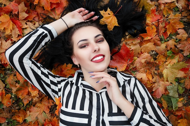 Schönheit, Leute, Jahreszeit und Gesundheitskonzept - hübsches Mädchen liegt im gelb-roten Herbstlaub