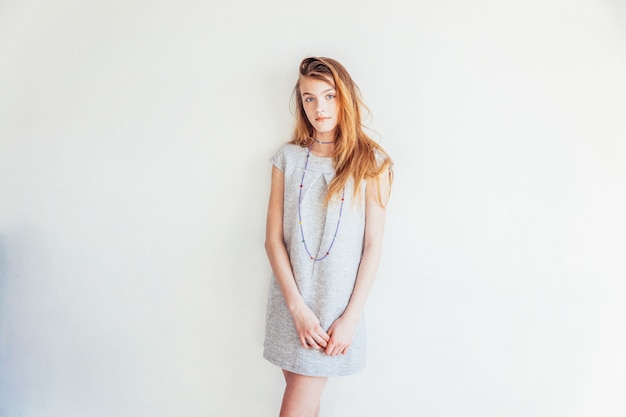 Schönheit teenager-mädchen. porträt junge jugendlich frau im grauen kleid gegen weiße wandwand. europäische frau.
