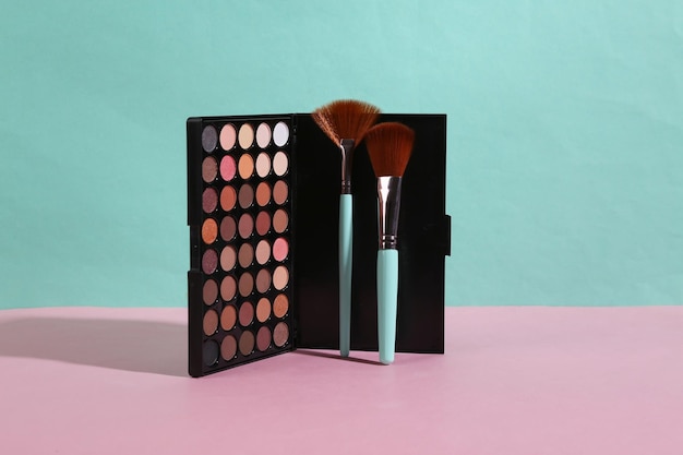 Schönheit und Mode minimalistische Szene Lidschatten-Palette und Make-up-Pinsel auf einem blau-rosa Pastellhintergrund mit trendigen Schatten Kreatives Layout