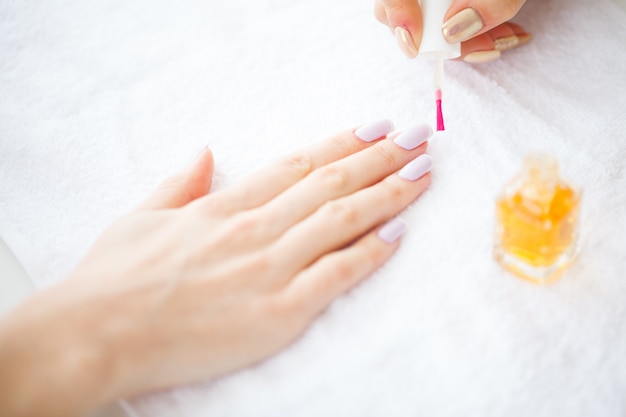 Schönheit und Pflege. Schöne Frauenhände mit perfekter Maniküre. Maniküre-Meister, der Nagellack in einem Schönheitssalon aufträgt. Schönheitstag. Spa Maniküre. Hand- und Nagelpflege