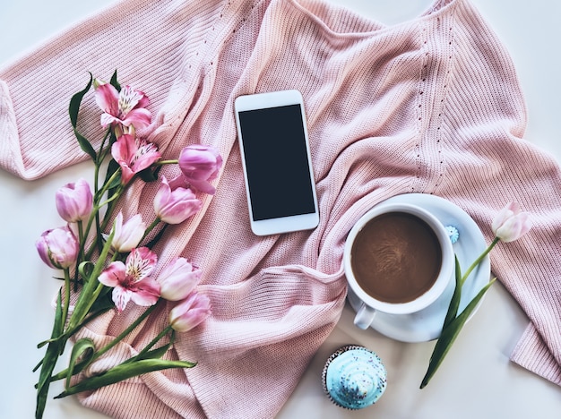 Schönheit und zart. Hochwinkelaufnahme von Pullover, Blumen, Smartphone, Tasse Kaffee,