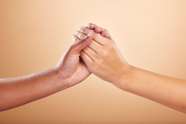 Schönheits-Hautpflege und Unterstützung mit Frauen, die sich im Studio auf einem beigen Hintergrund an den Händen halten, um Gemeinschaft oder Motivation zu schaffen. Vertrauen Sie Natur- und Kosmetikprodukten mit Modellfreunden, die in Einigkeit oder Solidarität verbunden sind