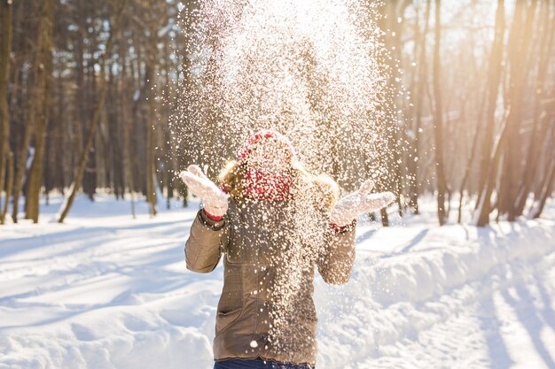 Schönheits-Mädchen bläst Schnee im frostigen Winterpark. Draußen. Fliegende Schneeflocken.