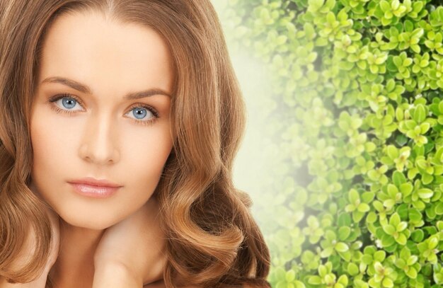 Schönheits-, Menschen- und Ökologiekonzept - schöne junge Frau, die ihre Gesichtshaut auf grünem Hintergrund berührt